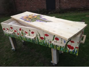Een kist van onbehandeld hout, beschilderd met klaprozen en korenbloemen