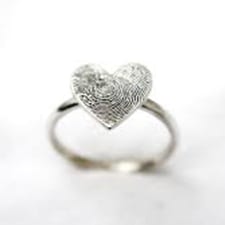 Een zilveren ring met een hartvormige kop, met een vingerafdruk erin