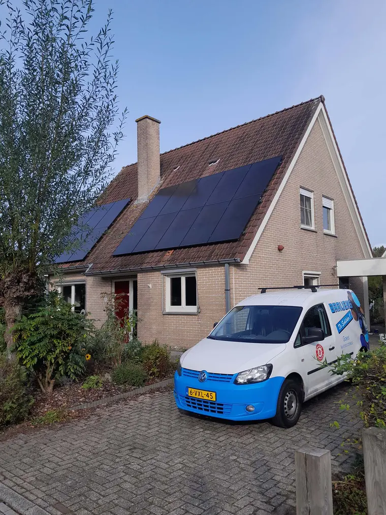 Een woning met zonnepanelen op het dak en een wit-blauwe bus van Baaijens op de oprit.