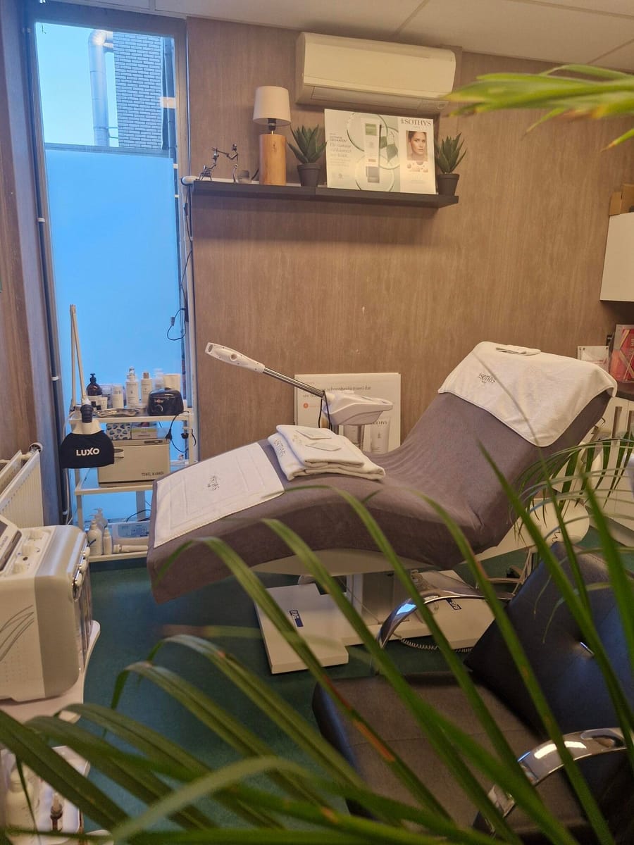 De behandelstoel in de salon, met handdoeken klaargelegd en een varenblad op de voorgrond.