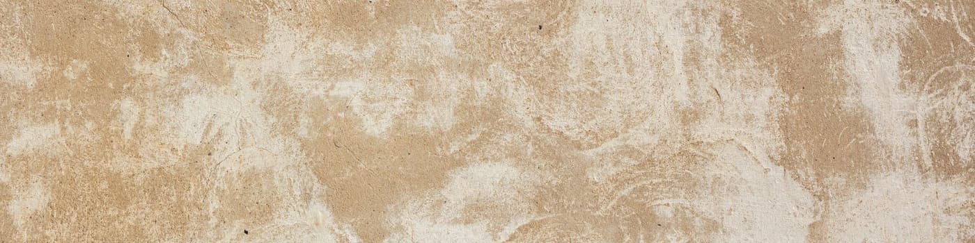 Een verweerde beige pleisterwand, van dichtbij.