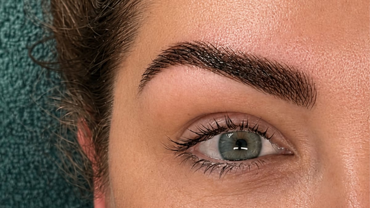 Close-up van een wenkbrauw en een oog tegen een donkergroene handdoek.