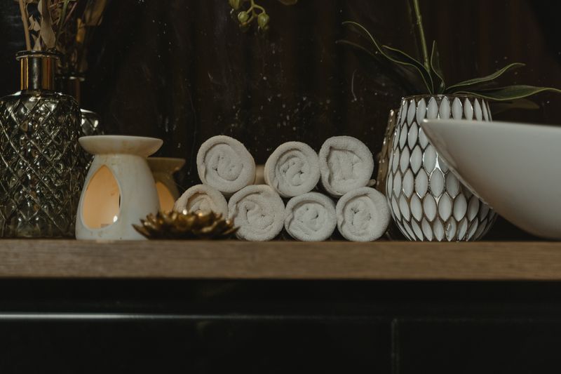 Opgerolde handdoeken en een geurbrander op een houten kast in de salon