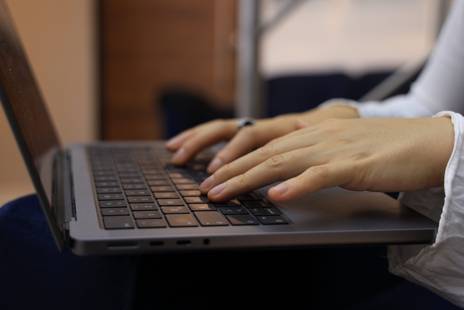 Twee handen die typen op het toetsenbord van een laptop