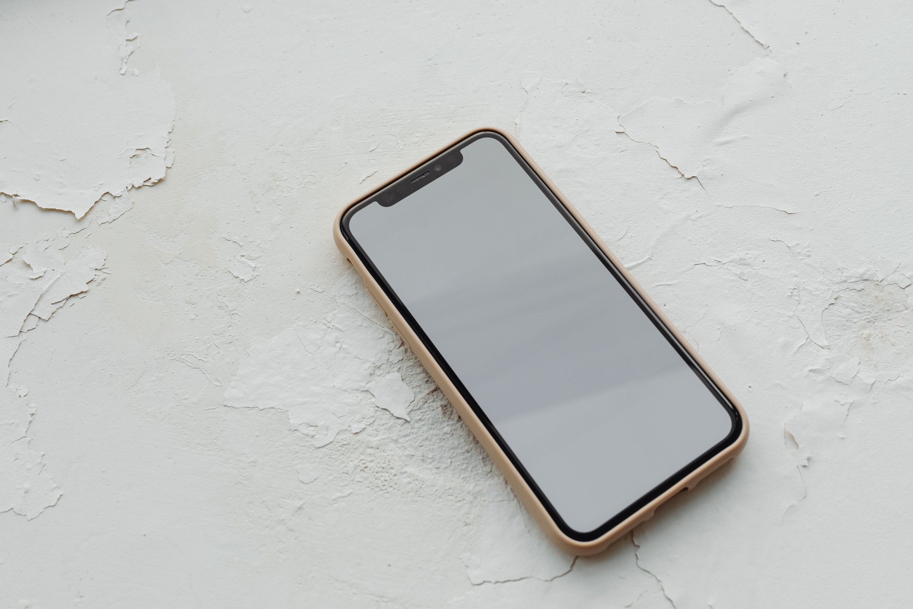 Een telefoon met een leeg scherm op een witte, gebarsten pleisterlaag
