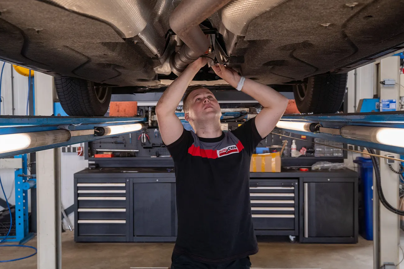 Monteur van Dahab Auto's werkt onder een geheven auto in de eigen werkplaats