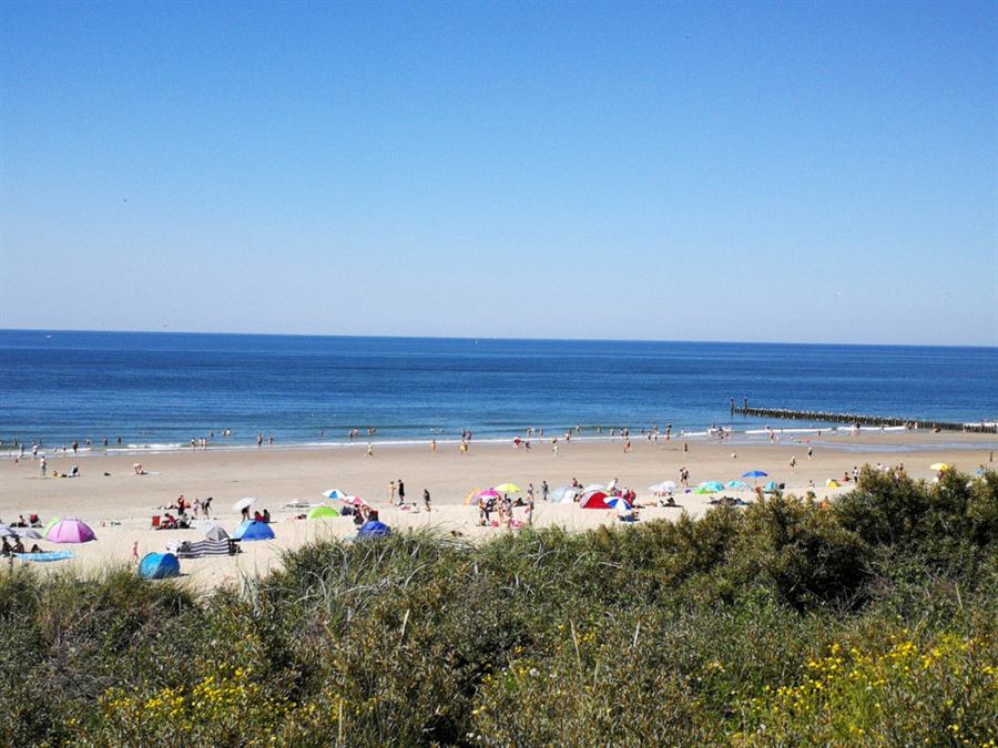 Zomers strand bij Domburg met parasols en badgasten, gezien vanaf de duinrand