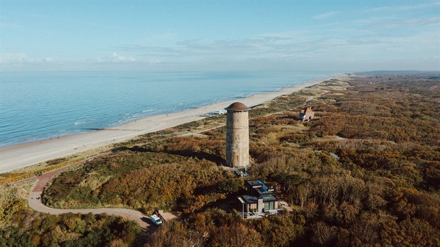 De watertoren van Domburg tussen de duinen, met het strand en de kustlijn vanuit de lucht