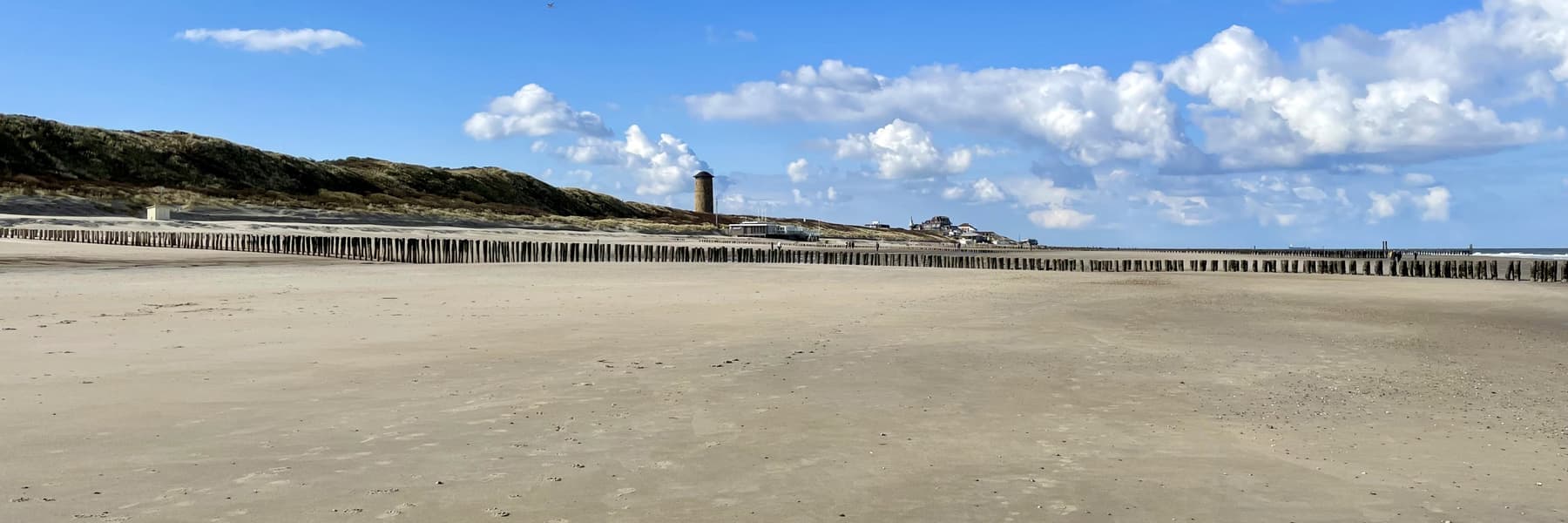 Breed leeg strand bij Domburg met een lange rij paalhoofden en de watertoren op de duinen.