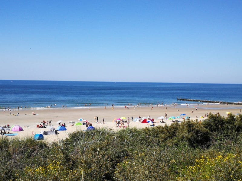 Het brede strand van Domburg gezien vanaf de duinen op een zomerse dag