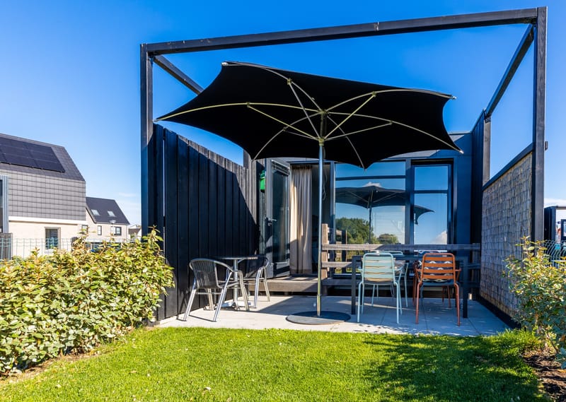 Terras met parasol, tuintafel en stoelen bij een van de vakantiehuizen
