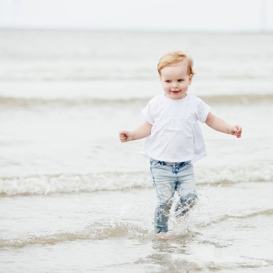 Peuter rent door de branding aan het strand
