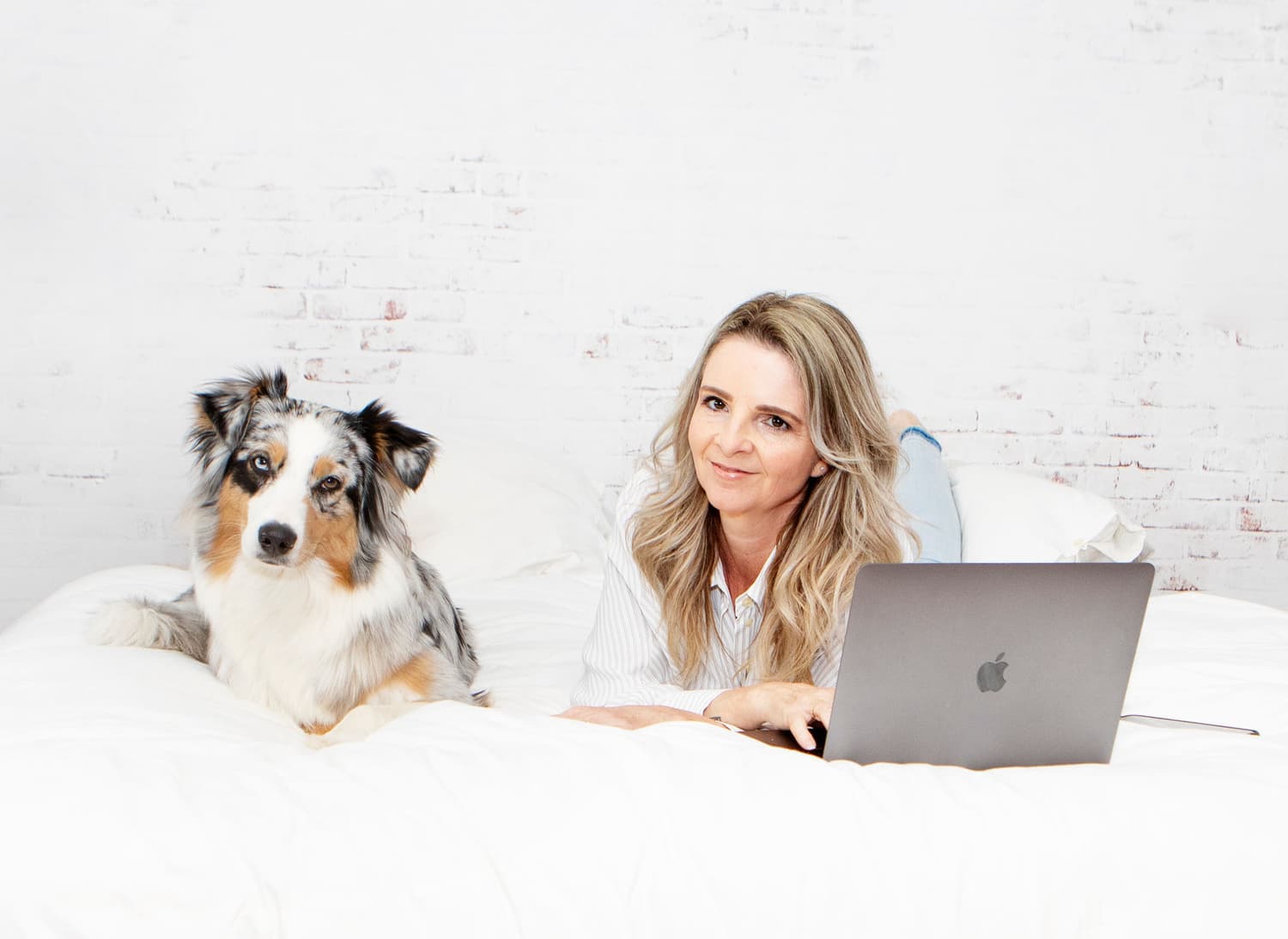 Esther Schog met haar hond op een wit bed in haar studio