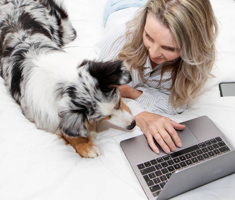 Esther Schog achter haar laptop met haar hond naast zich