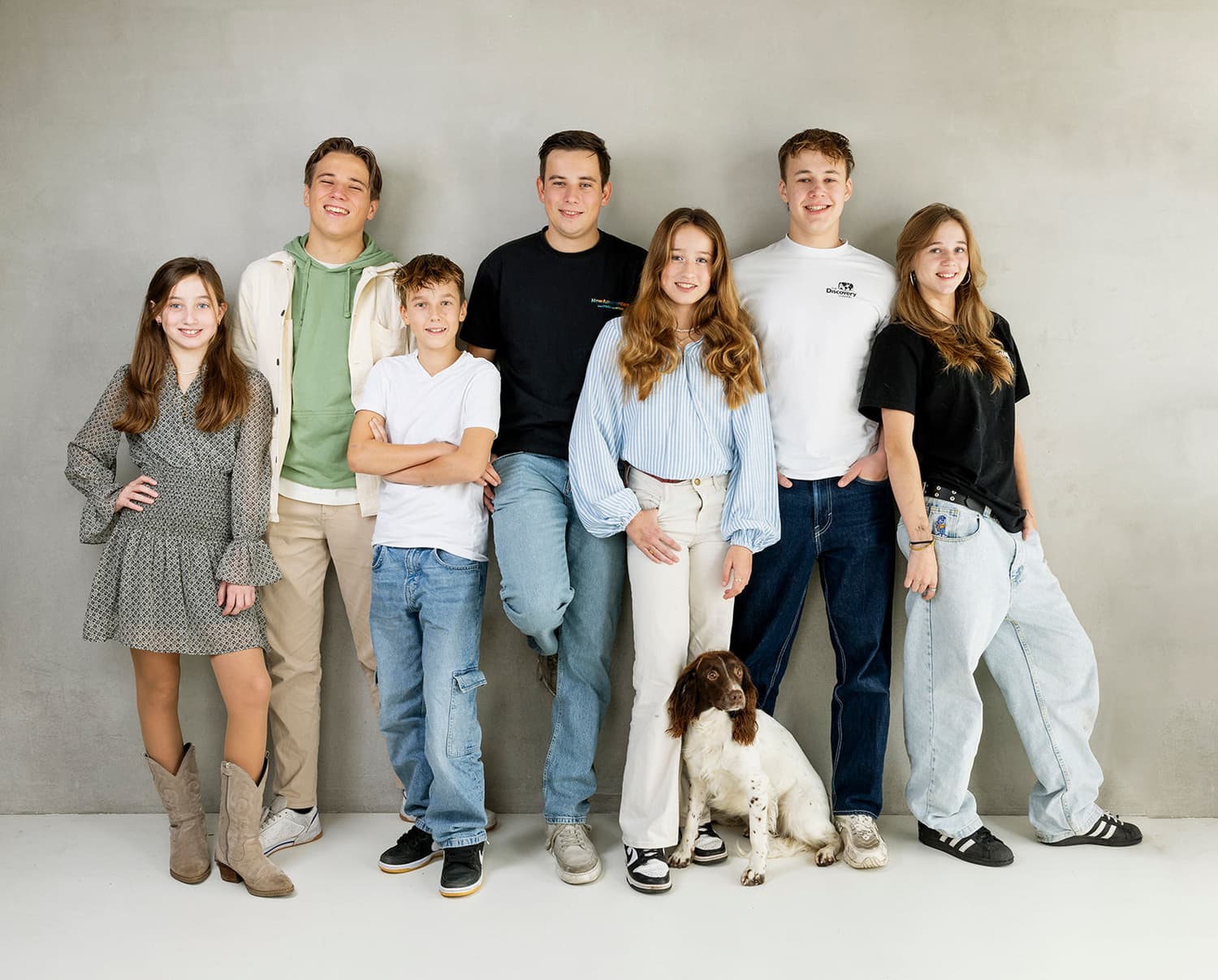 Grote familie met kinderen en hond samen tegen een grijze achtergrond