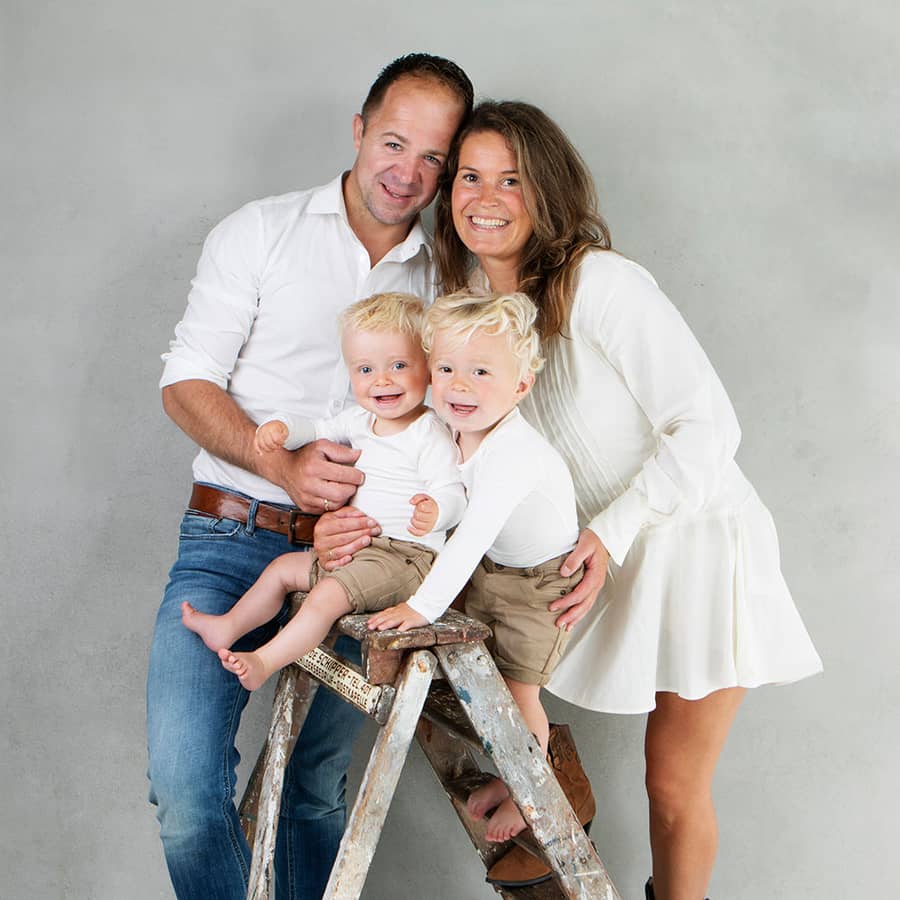 Gezin met twee jonge kinderen bij een houten ladder in de studio