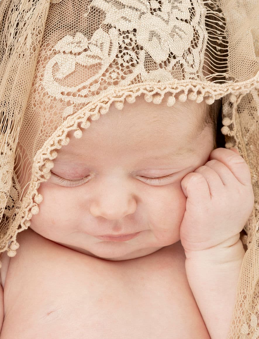 Pasgeboren baby met gesloten oogjes onder een kanten mutsje