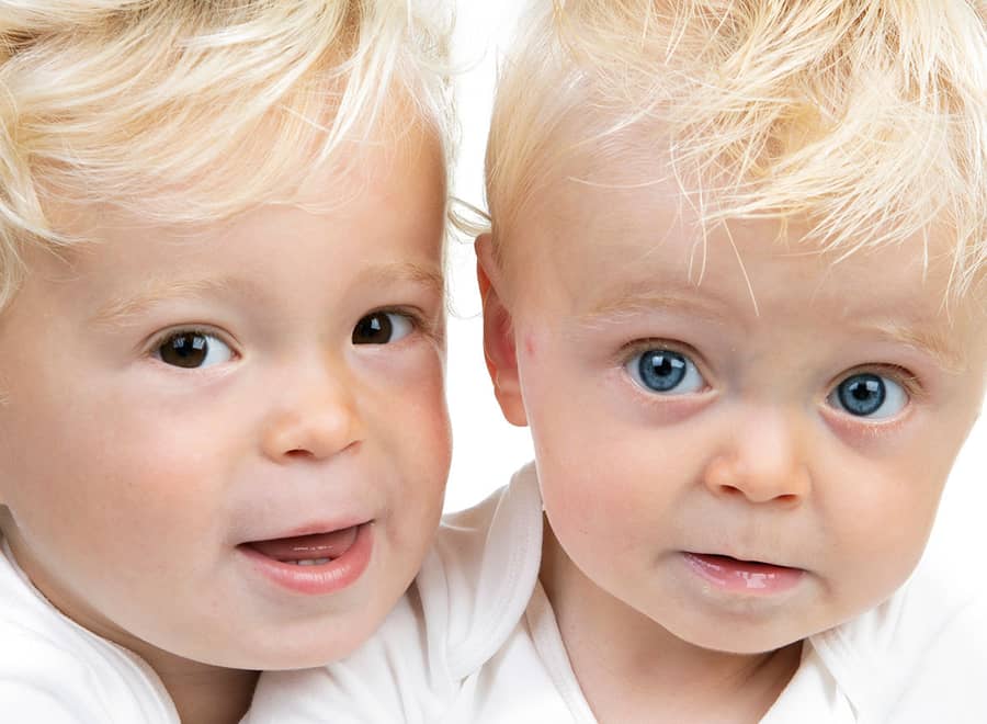 Twee blonde peuters dicht bij elkaar tegen een lichte achtergrond