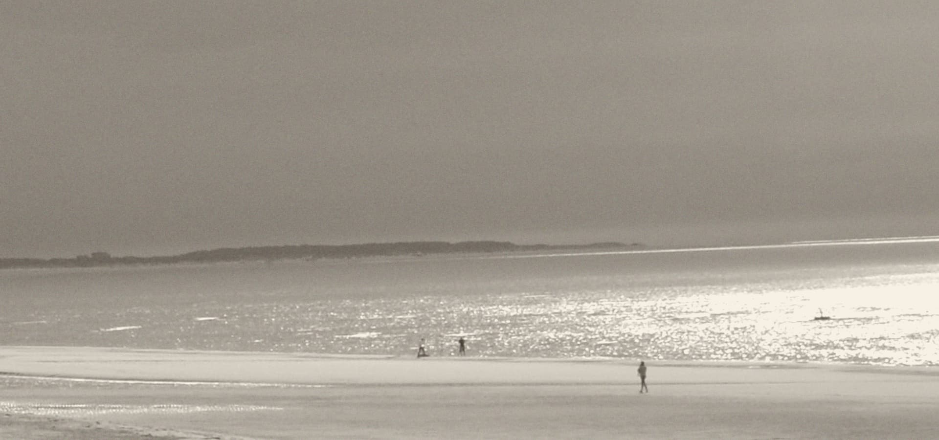 Het strand en de zee bij eb in Zeeland, met een enkele wandelaar in de verte