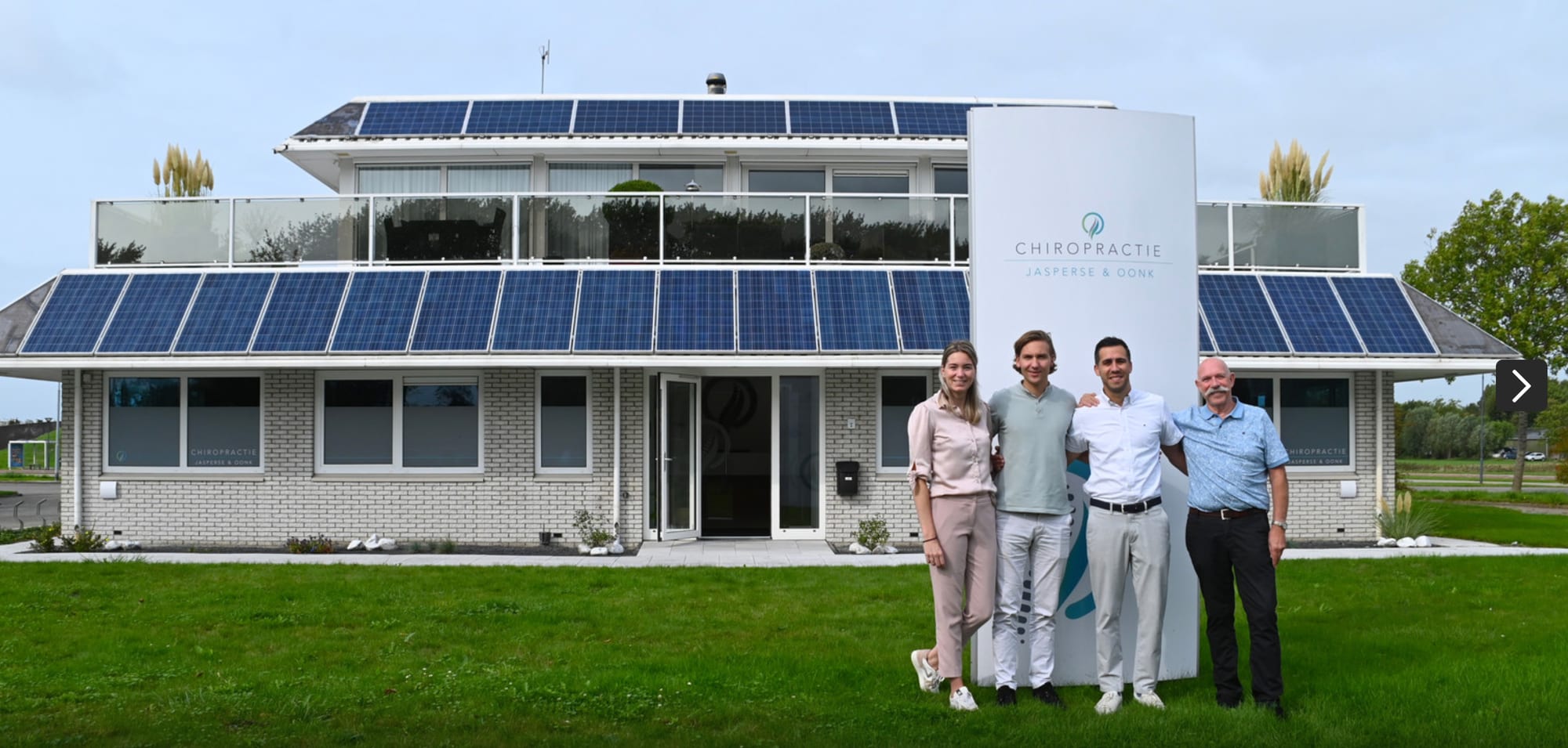 Het praktijkpand aan de Nieuwe Vlissingseweg in Vlissingen, met zonnepanelen over het dak en een witte zuil met de naam Chiropractie Jasperse en Oonk