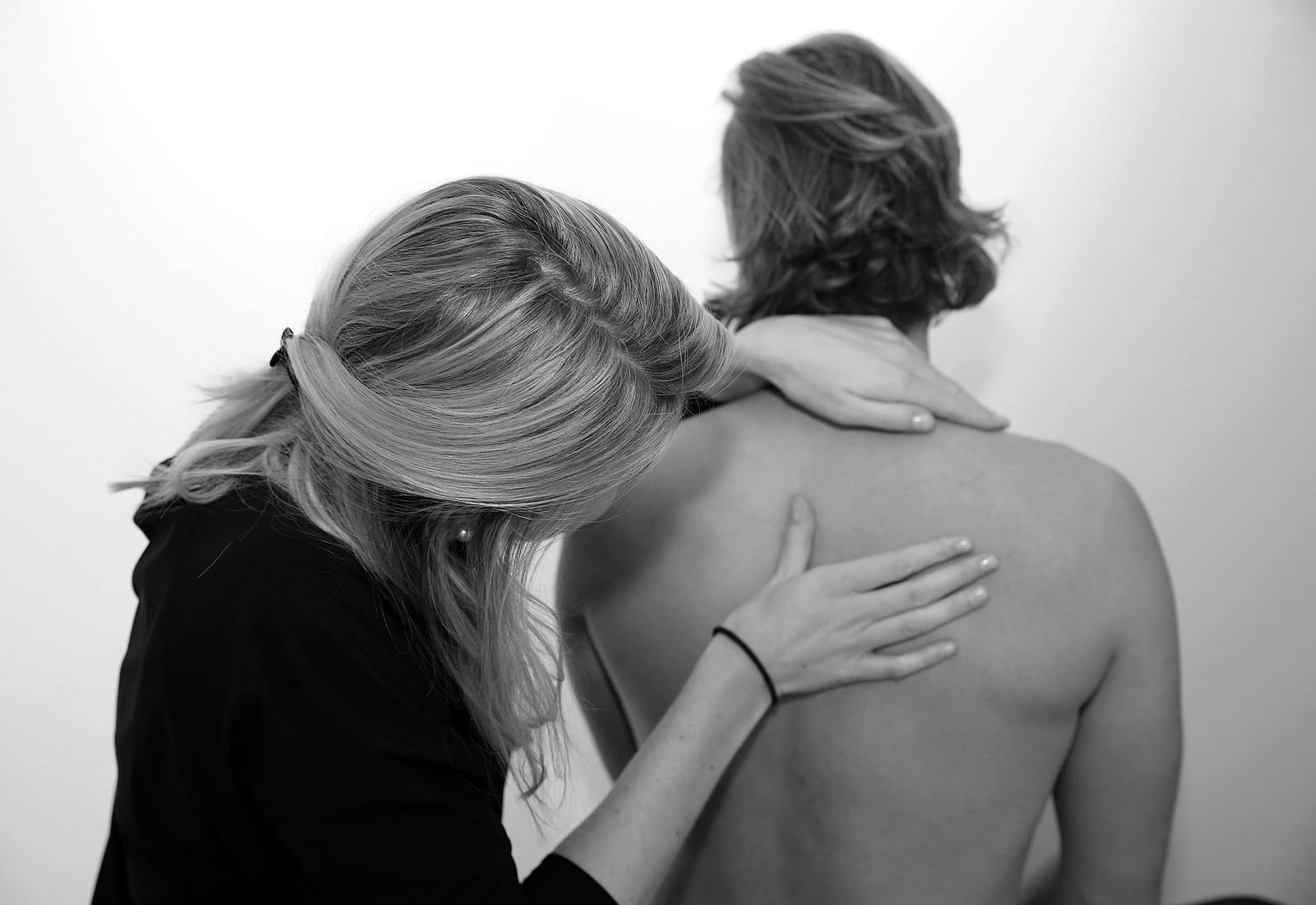Een chiropractor onderzoekt de rug van een patiënt met beide handen