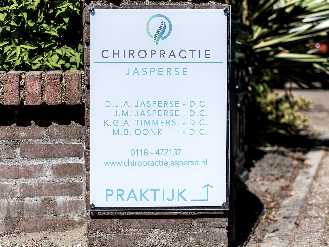 Het praktijkbord aan de straat met de namen van de chiropractoren en het telefoonnummer