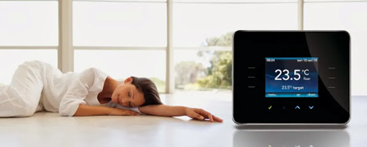 Iemand ligt ontspannen op een lichte vloer naast een digitale thermostaat die 23,5 graden aangeeft