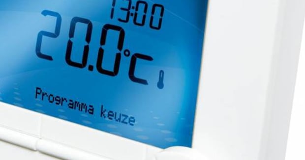 Close‑up van een blauw verlicht thermostaatdisplay dat 20.0 graden Celsius en 13:00 aanwijst.