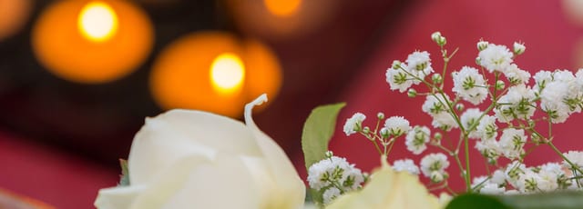 Brandende kaarsen met kleine witte bloemen ernaast, in warm licht