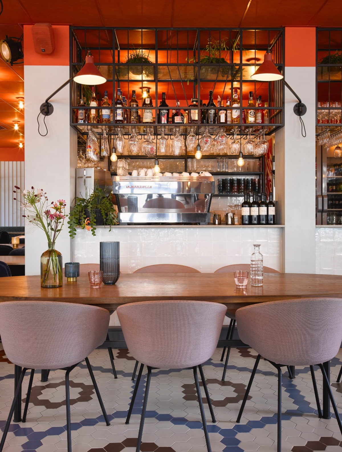 De bar met flessenrek, hanglampen en espressomachine