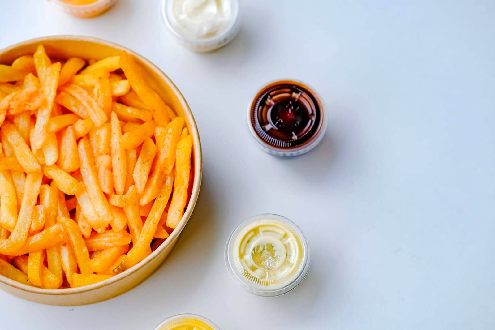 Een portie friet met verschillende sauzen ernaast