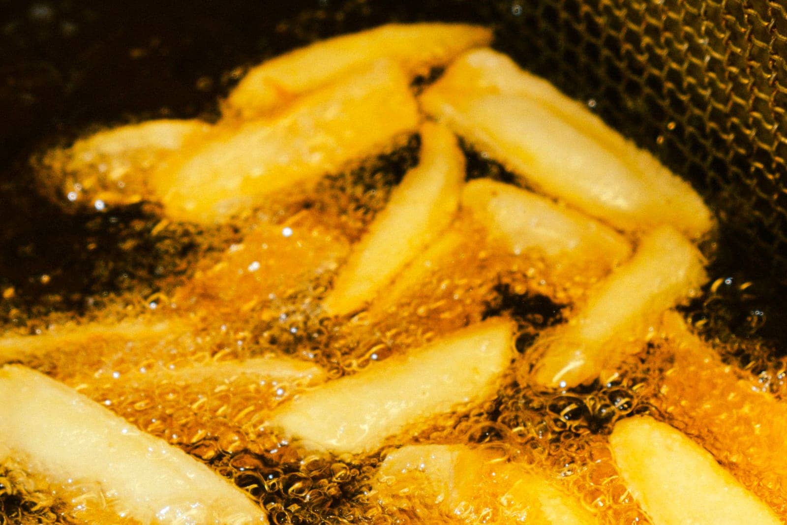 Dik gesneden friet die goudbruin bakt in hete olie