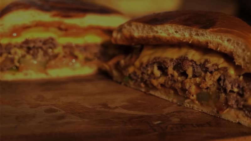 Doorgesneden burger met gesmolten kaas op een houten plank