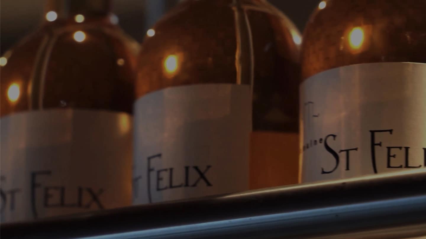 Flessen met witte etiketten op een plank, warm verlicht door kleine lampjes