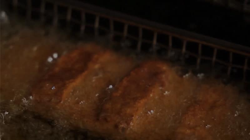 Twee goudgebakken snacks in borrelend frituurvet