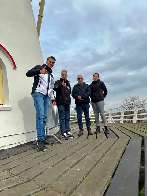 Vier mensen op de stelling van een witte molen, twee van hen in bedrijfskleding van Franse.