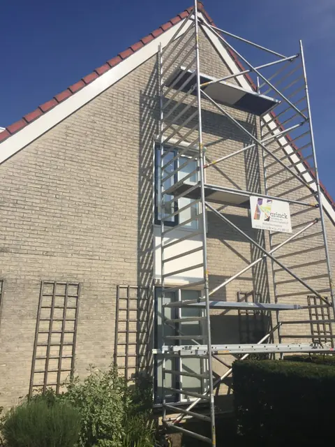 Steiger opgebouwd tot aan de dakrand tegen de punt van een gevel.