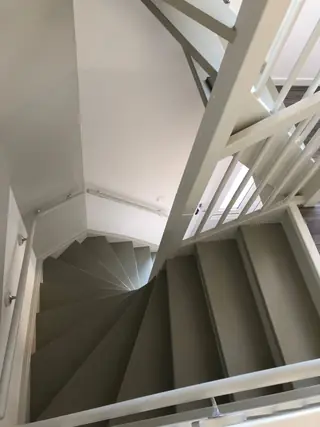 Wit geschilderd trapgat met grijze traptreden, van boven gezien.