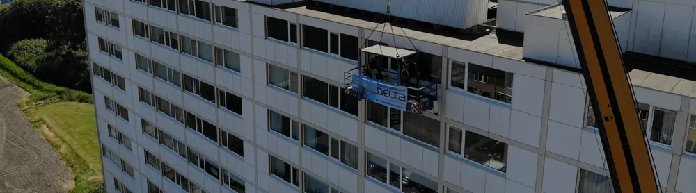 Gevel van een galerijflat op Walcheren van dichtbij, met de werkbak van Delta halverwege ertegenaan.