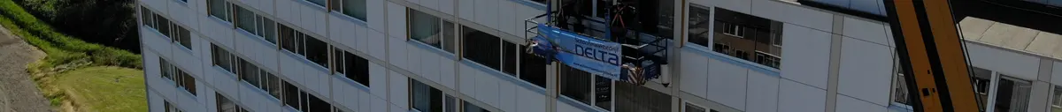 Gevel van een galerijflat op Walcheren van dichtbij, met de werkbak van Delta halverwege ertegenaan.