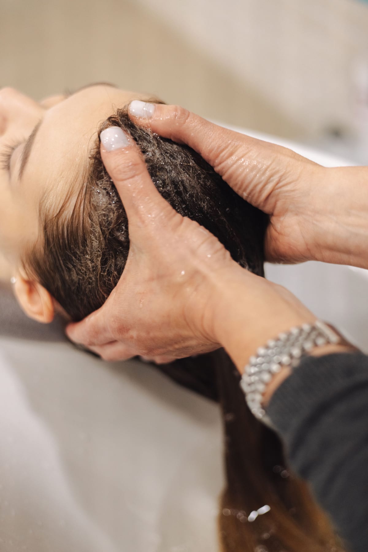 Twee handen masseren de hoofdhuid van een liggende vrouw tijdens de Japanse Head Spa.