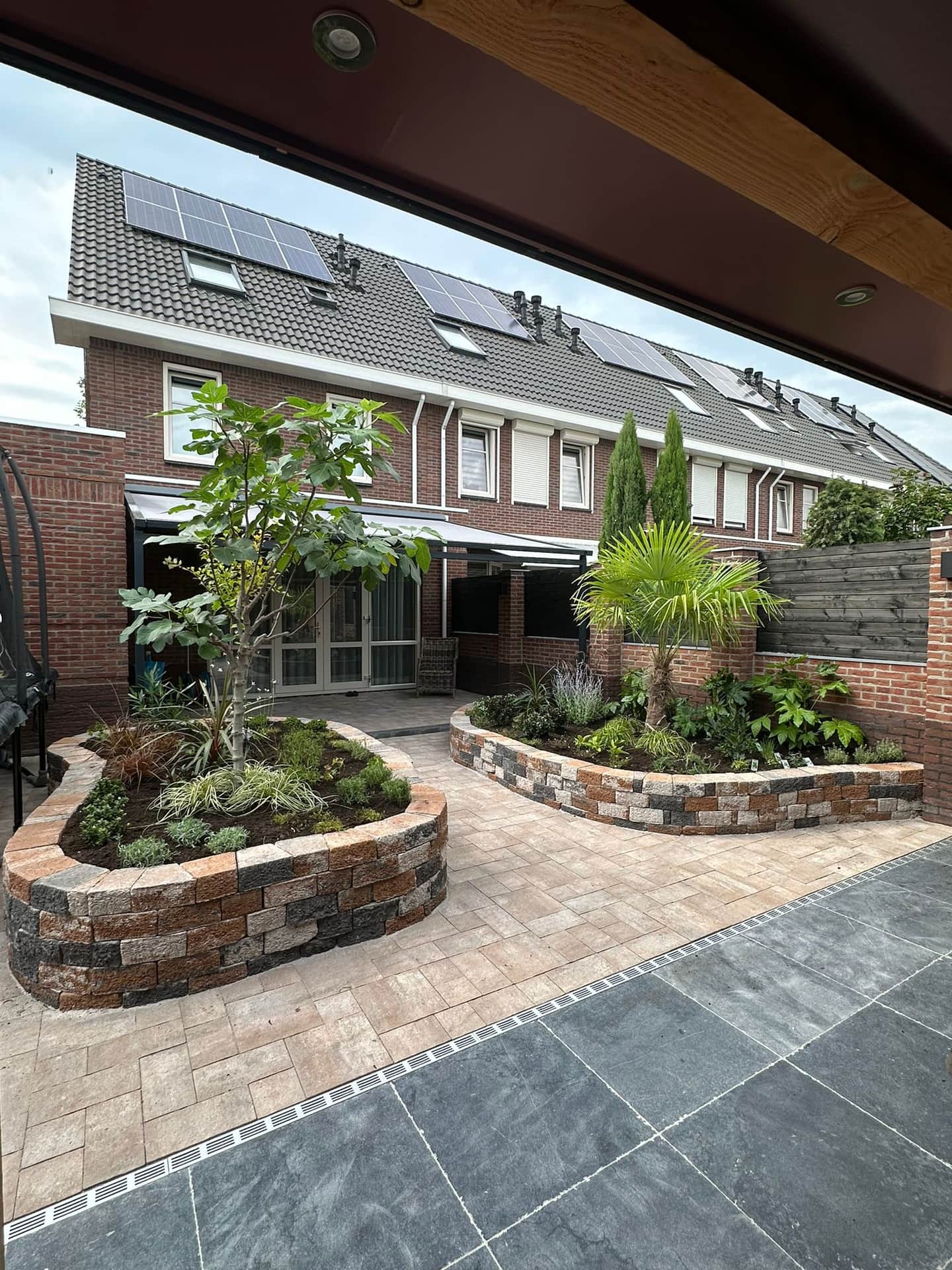 Binnentuin met verhoogde plantbakken van natuursteen en een terras in twee formaten tegels