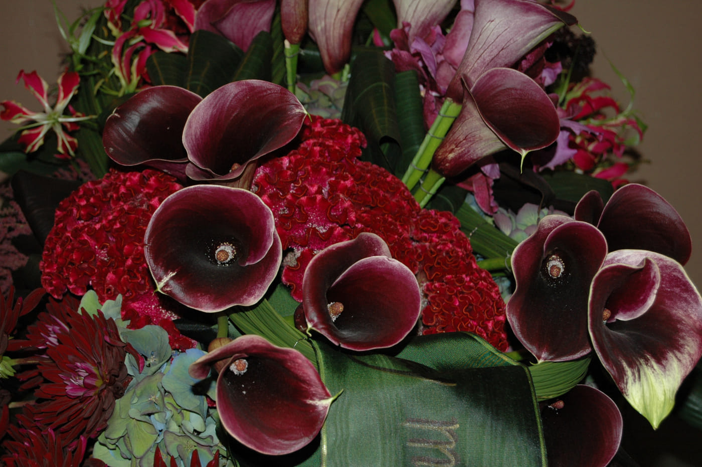 Rouwbloemstuk van donkere calla lelies en rode bloemen