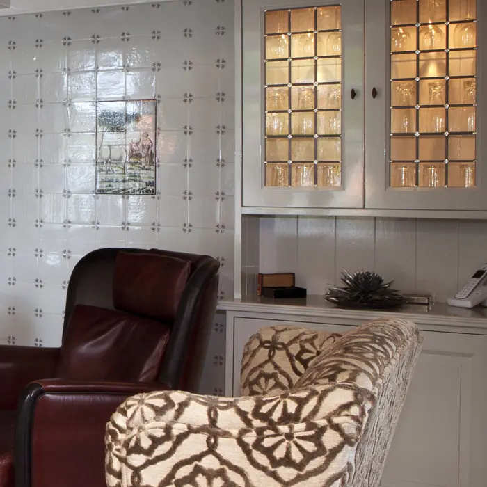Ingebouwde kast met glasdeurtjes en verlichting, naast een betegelde wand.