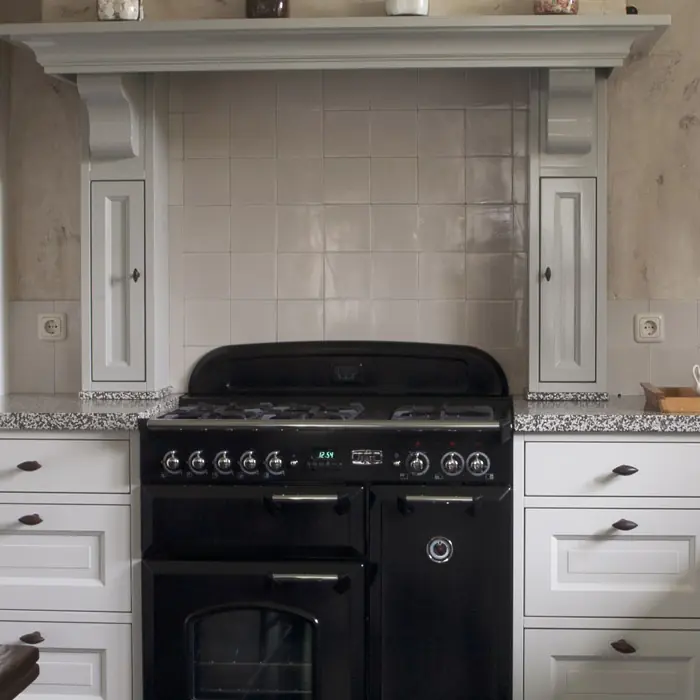 Klassieke keuken in gebroken wit met een schouw boven het fornuis en een stenen werkblad.