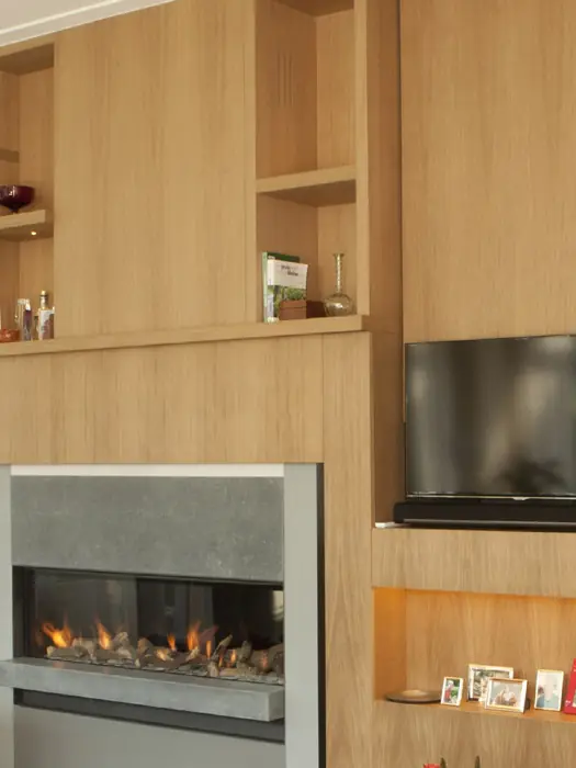 Detail van een eiken wandmeubel met open vakken, een boekenplank en een verlichte nis.