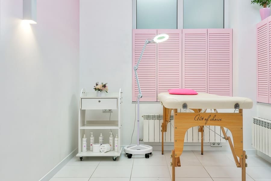 Een lichte behandelkamer met een behandeltafel en verzorgingsproducten.