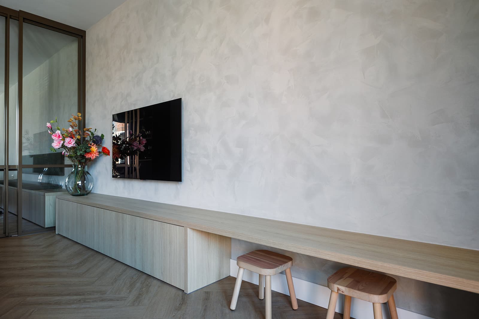 Rustige woonruimte met een houten wandbank tegen een gestucte wand