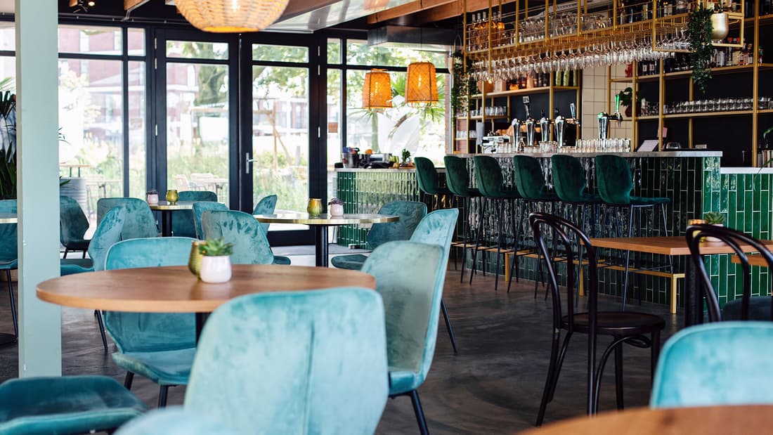 Interieur van Op Roose in Utrecht met bar en groene stoelen