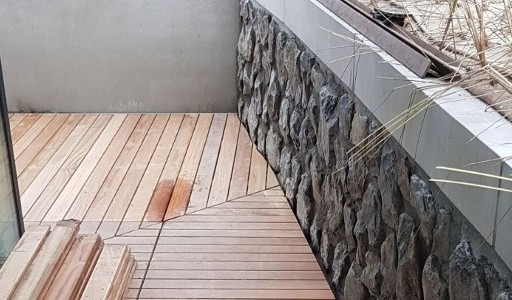 Houten vlonder tegen natuurstenen keermuur